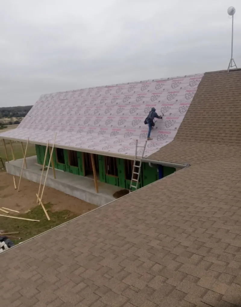 Worker preparing underlayment for a metal roof installation in Pepperell